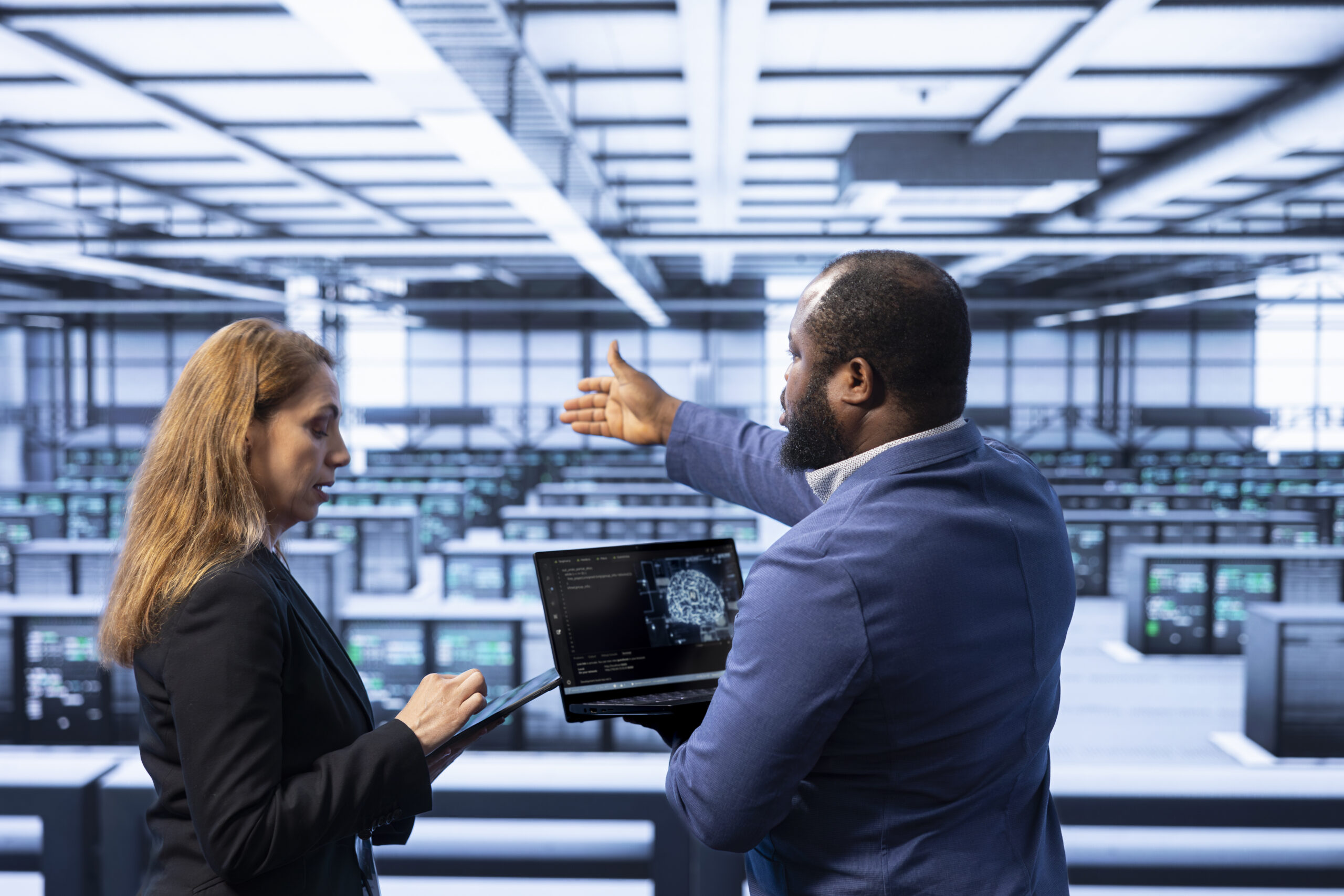 Team of technicians in data center using laptop to visualize artificial intelligence neural networks made up of interconnected nodes. Teamworking colleagues oversee AI systems processing information